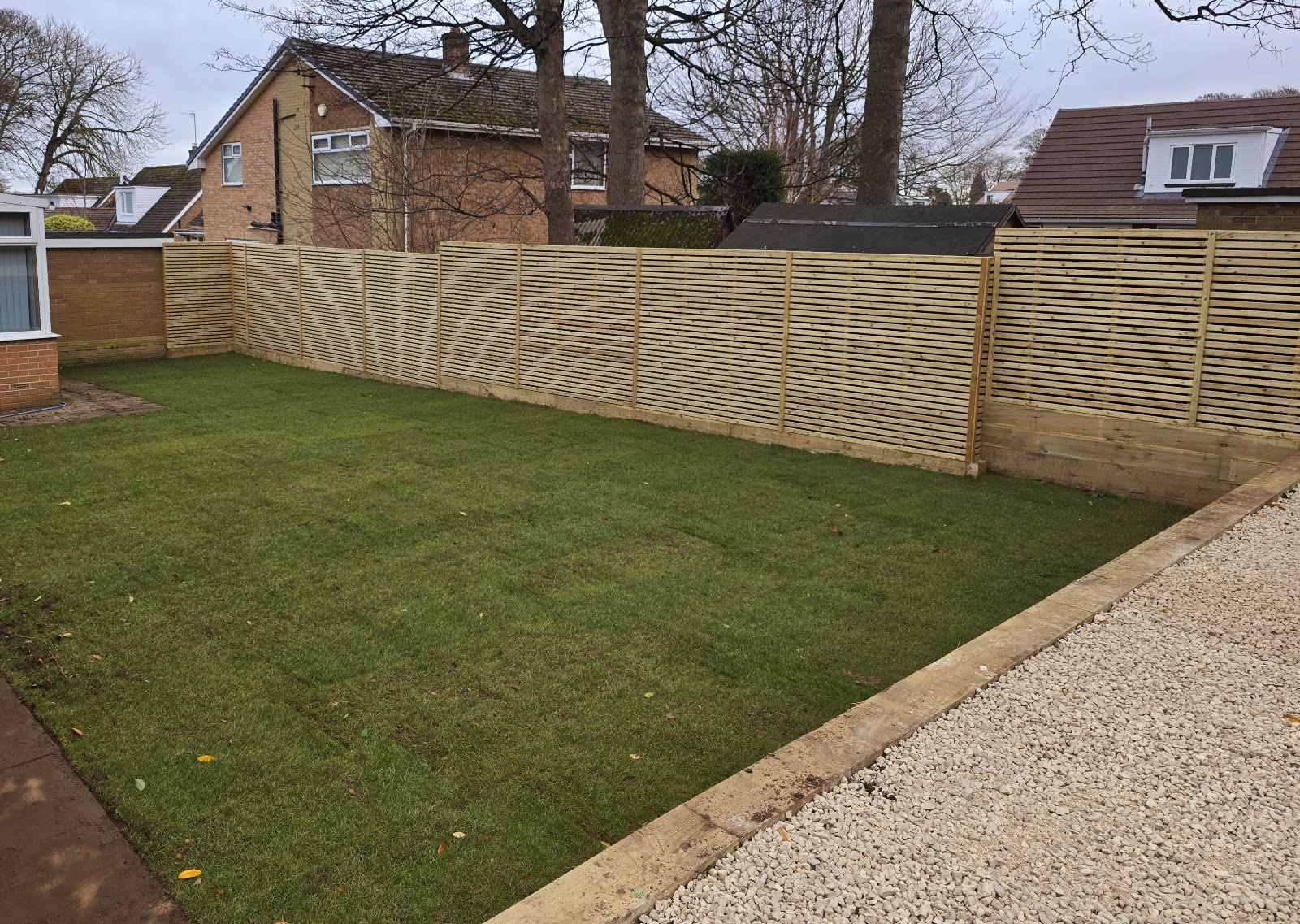Freshly laid lawn framed by new slatted fencing and a gravel border, maintained by Lofthouse Garden Services