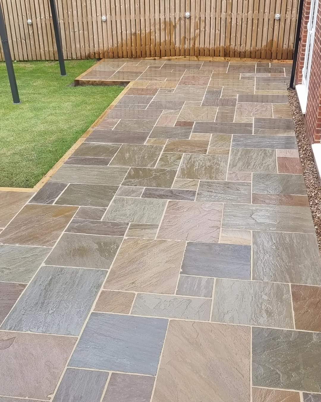 Riven Indian-stone patio laid by Lofthouse Garden Services beside a fresh lawn and slatted fence