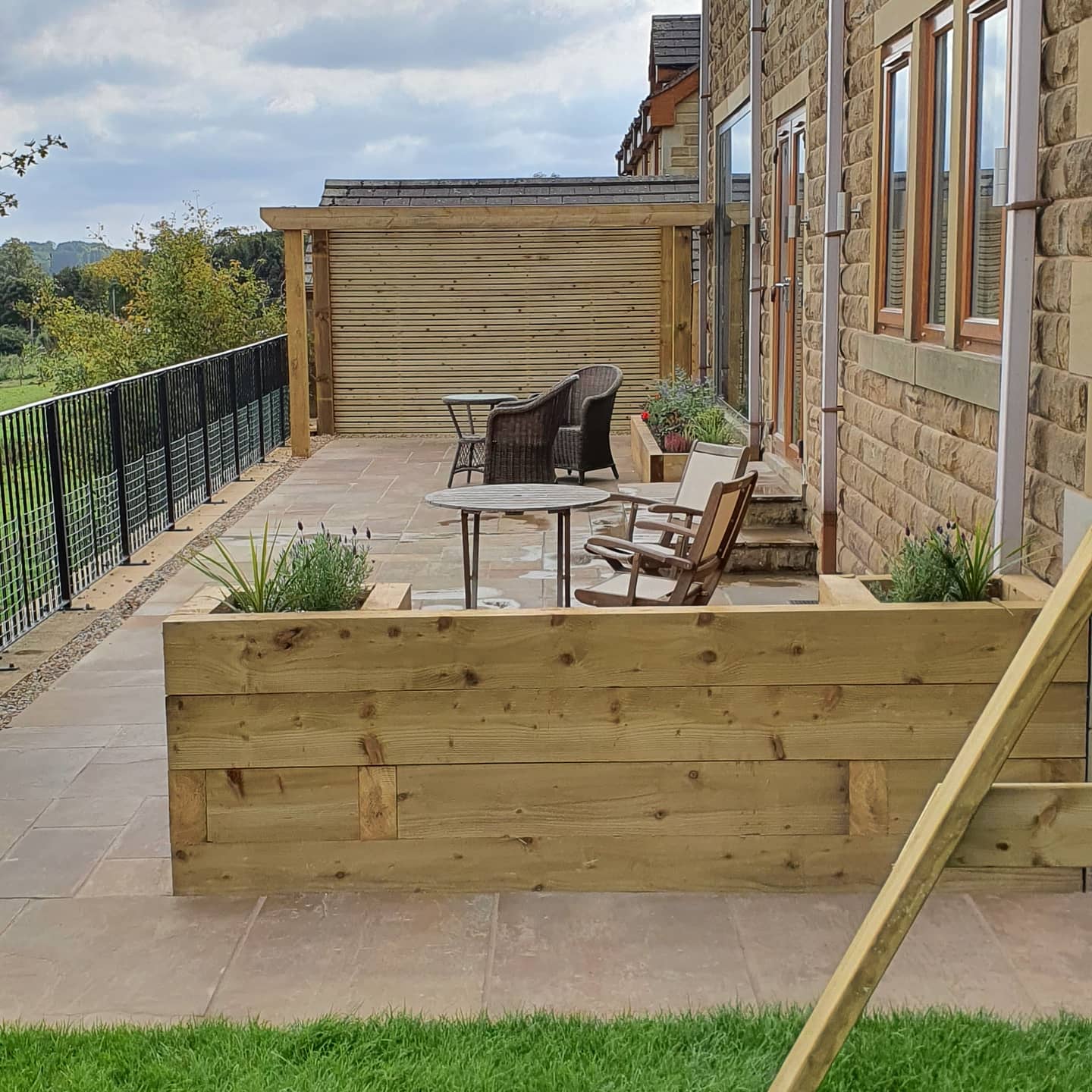Raised patio with pergola and planters overlooking open countryside