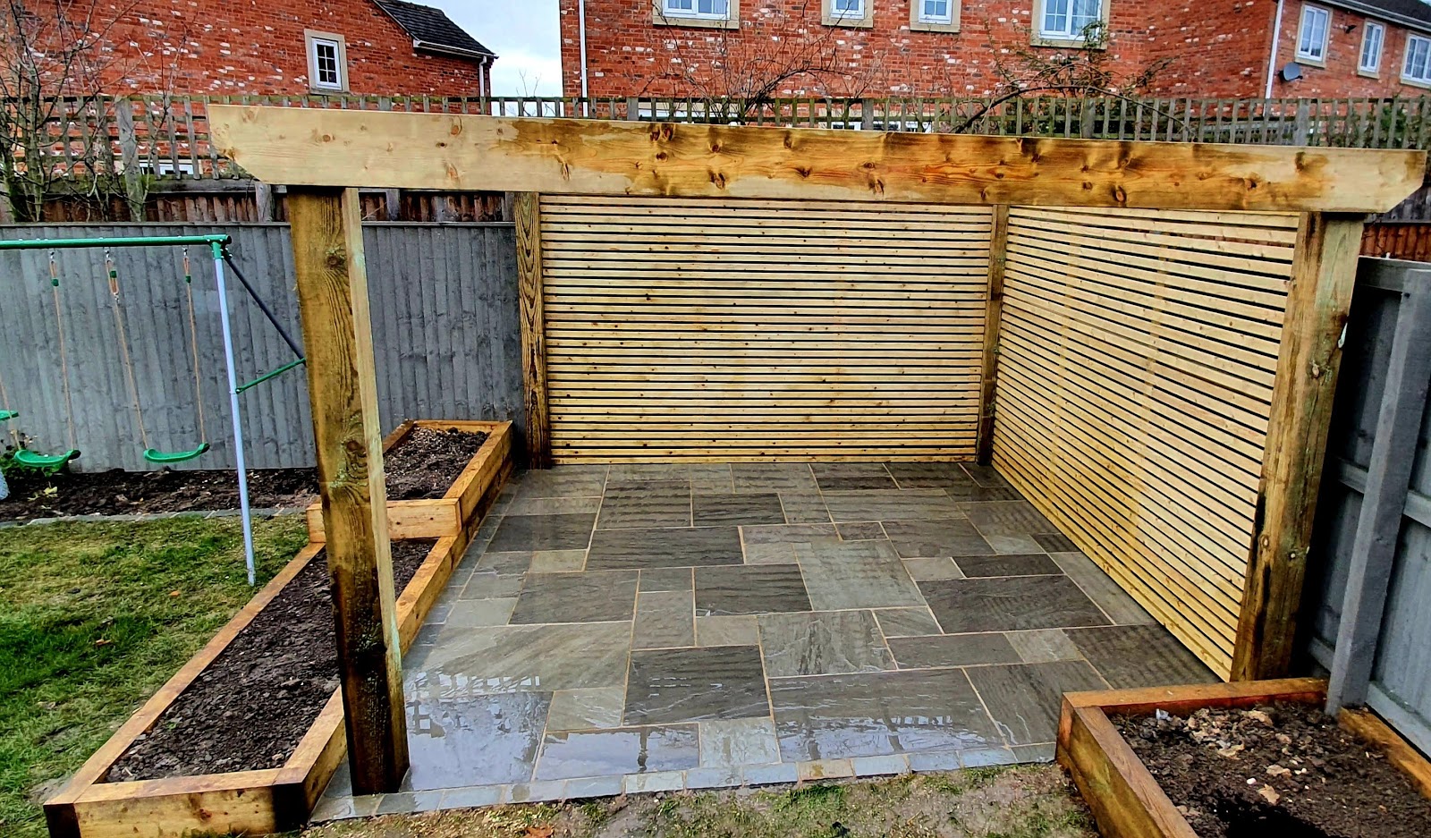 Covered pergola seating area with grey sandstone paving and sleeper planters